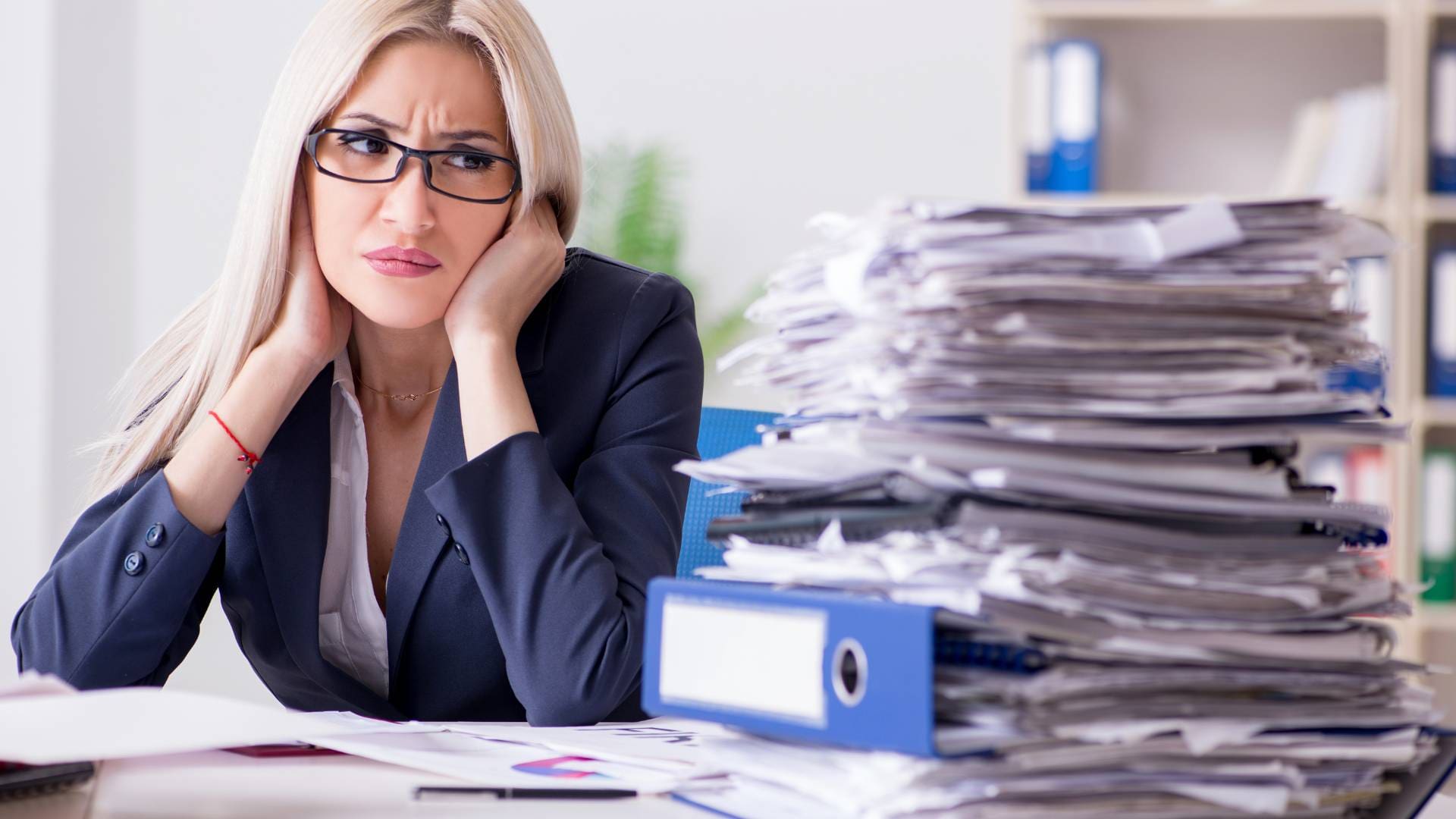 A business woman looking at a massive pile of paperwork. She's not happy.