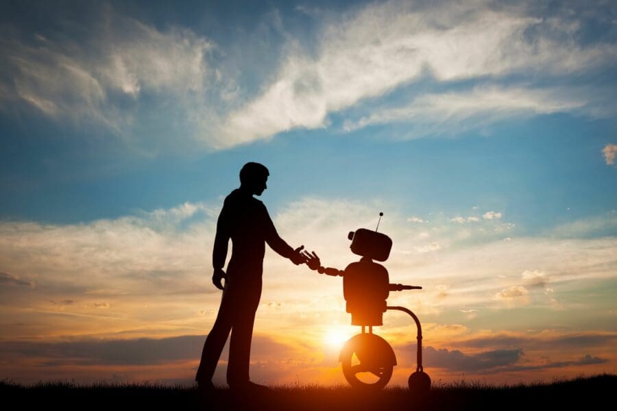 A robot and a human holding hands while walking with a sunset behind them.