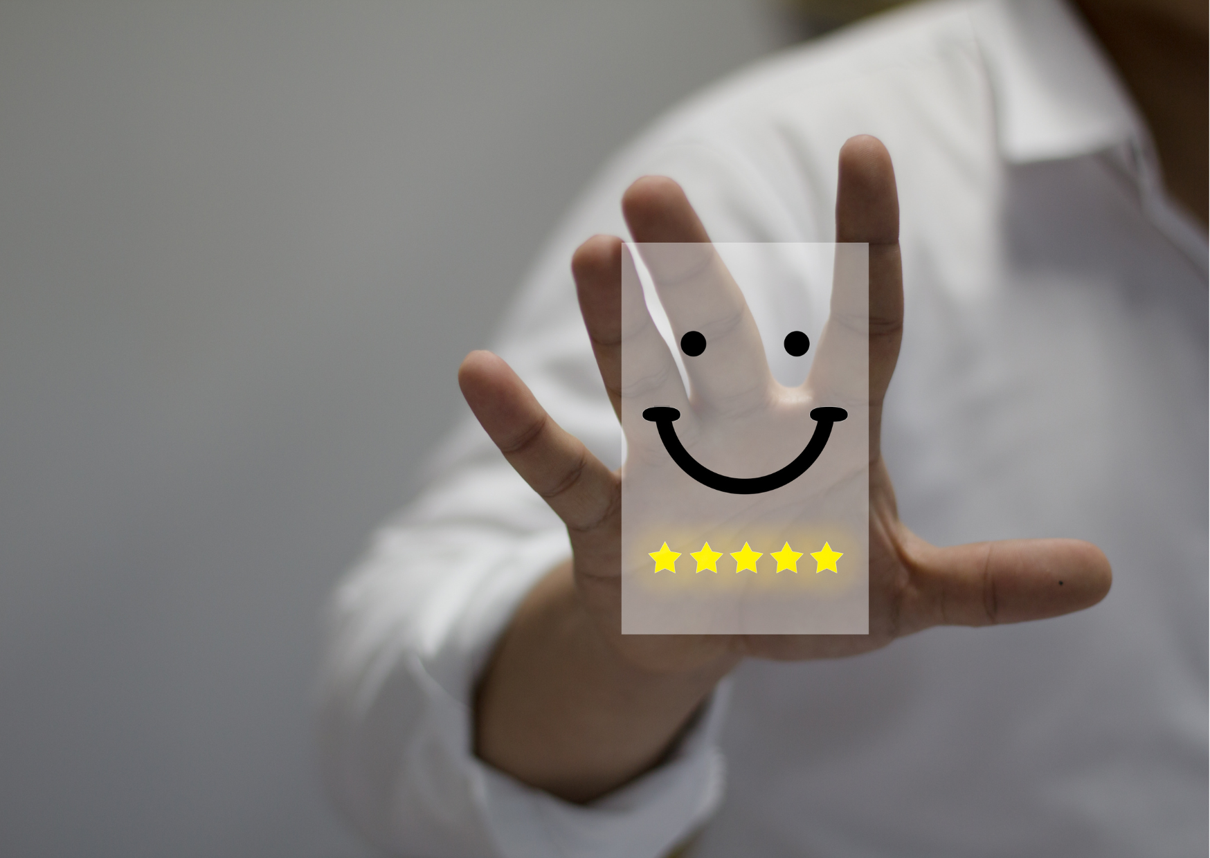 The edge of a person in a white shirt. They hold their hand up toward the camera, and over the hand is a smiley face adn 5 stars floating above.