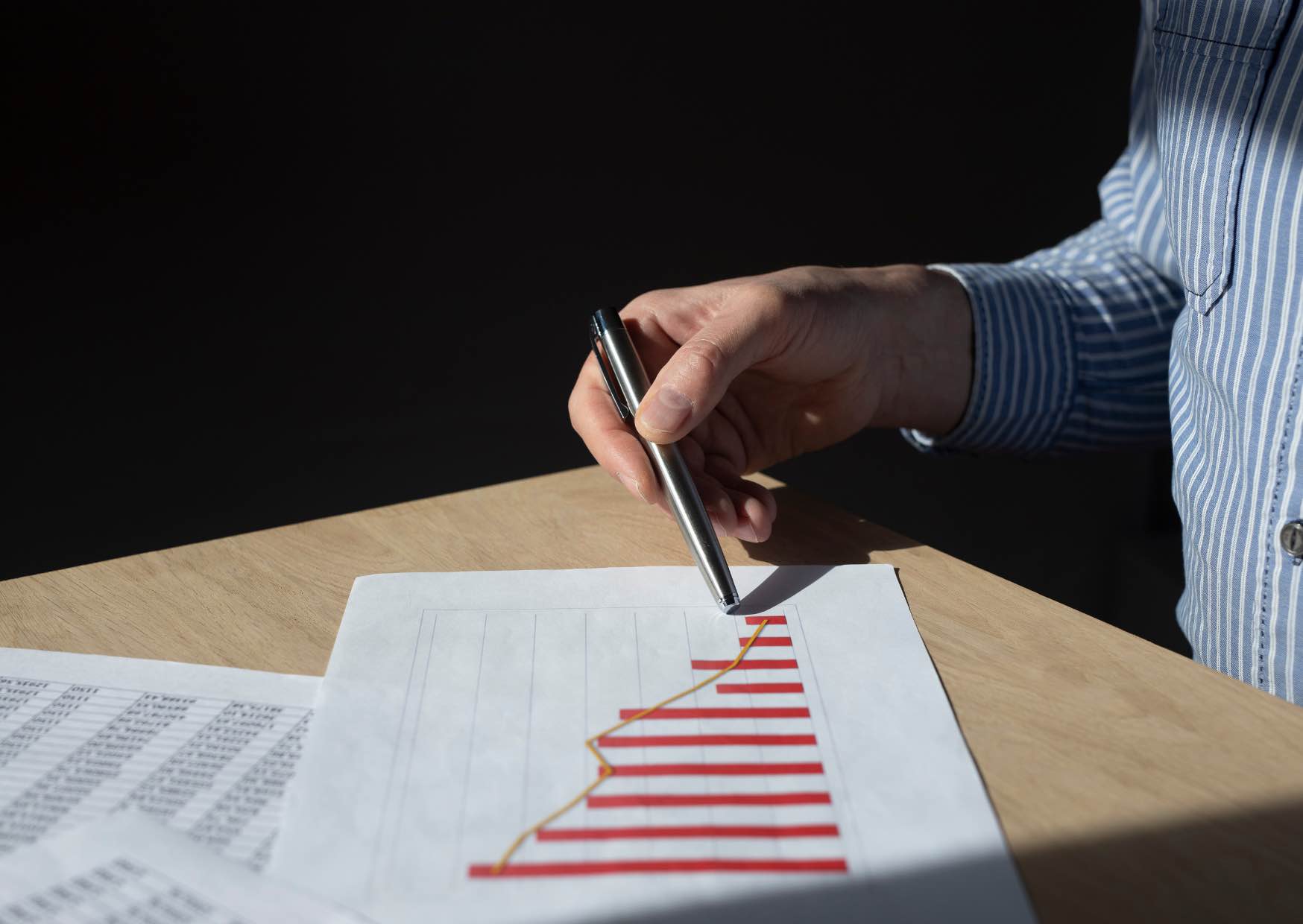 A hand with a pen checks a graph on loss in a dark room.